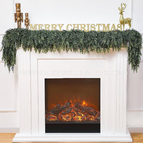 Decorative fireplace with Christmas mantel, garland, and 'Merry Christmas' sign.