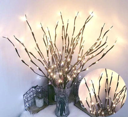 Decorative branches with lights in a vase on a white surface