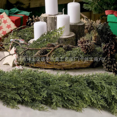 Decorative Christmas arrangement with candles, greenery, and pinecones on a wooden surface.