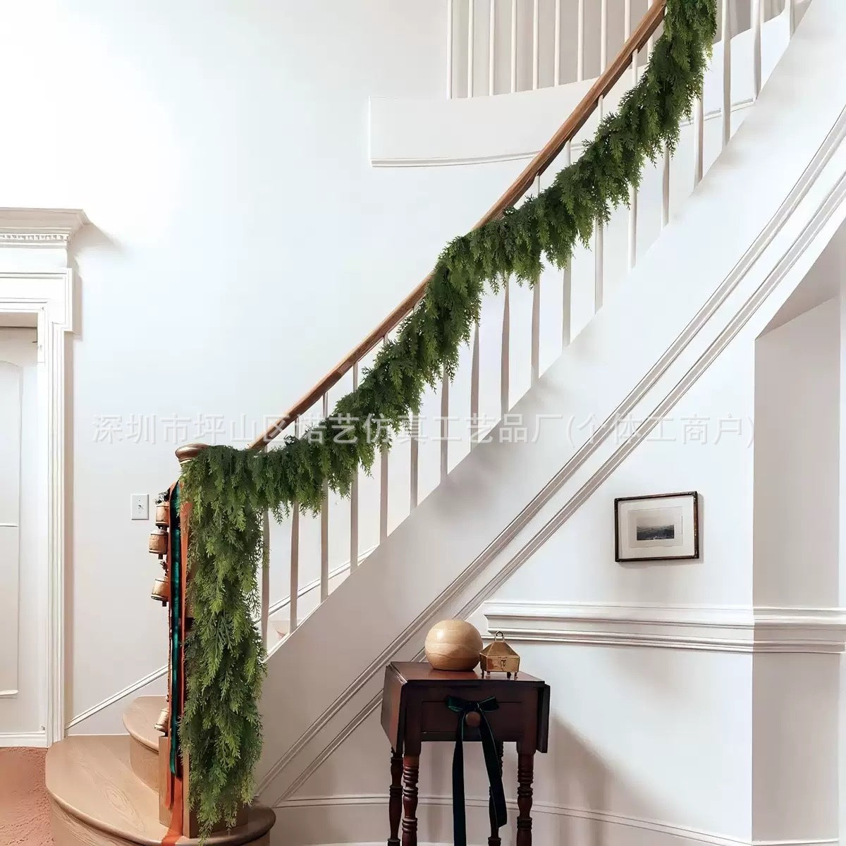 Staircase with green garland and a small table with decorative items in a home setting.