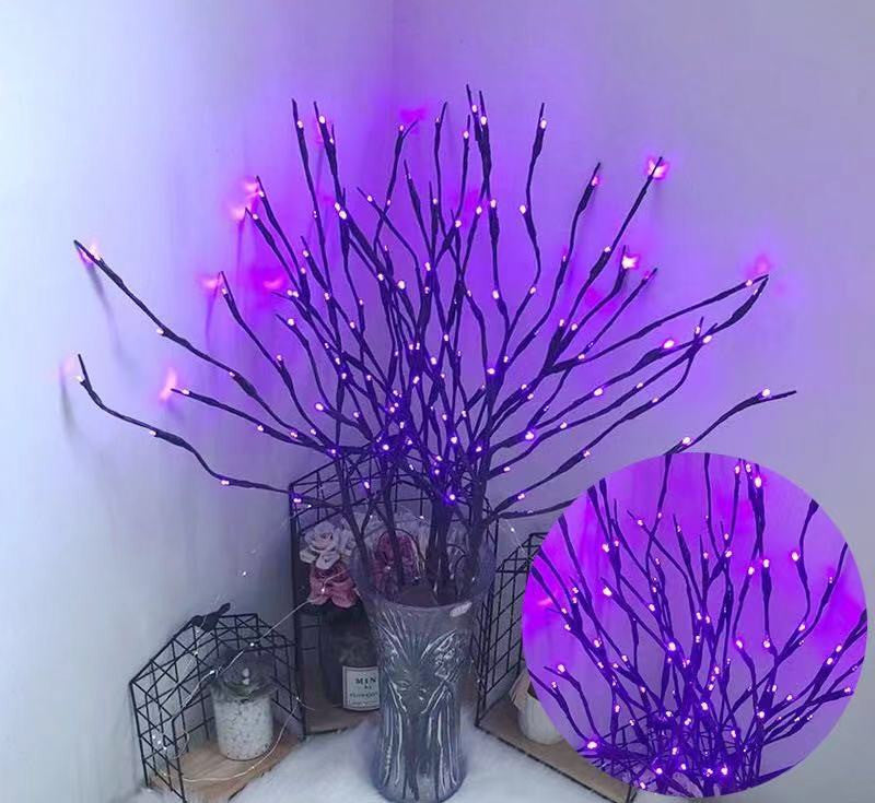 Decorative branches with purple LED lights in a vase against a white wall.