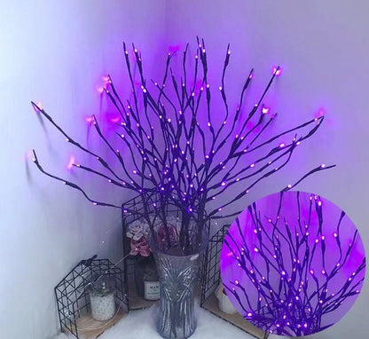 Decorative branches with purple LED lights in a vase against a white wall.