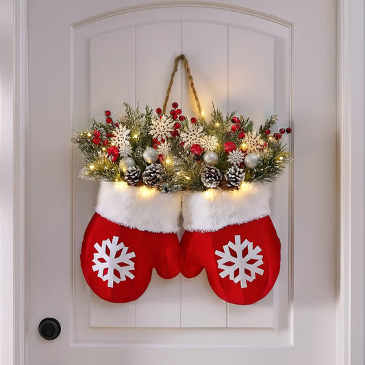 Decorative Christmas stockings with floral arrangement and lights on a white door.
