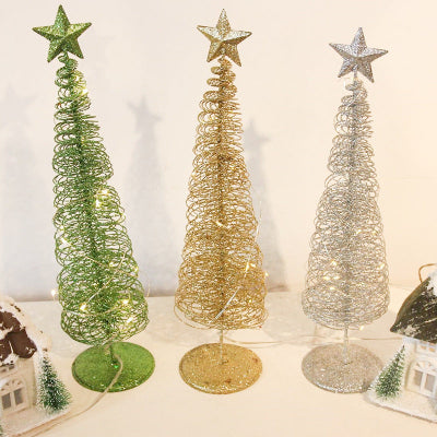 Three decorative Christmas trees in green, gold, and silver with star toppers on a white surface.